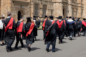 University students marching down the street in graduation robes and gowns
