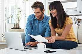Smiling couple look at laptop