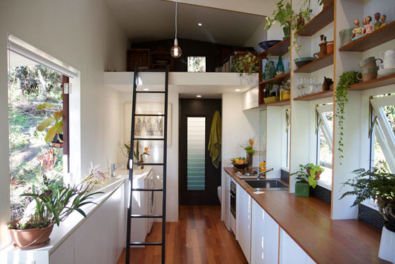 Internal view of a high spec tiny house with lots of light, wooden floors and a black steel ladder