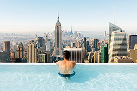 Man in pool, looking out at city view
