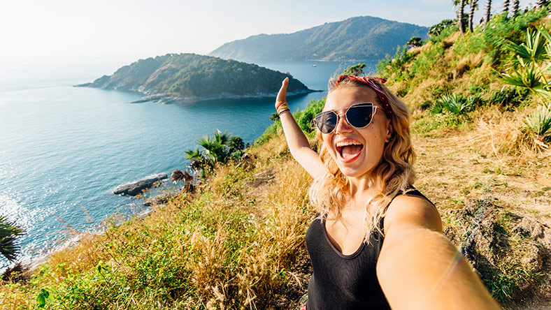 Woman taking selfie on mountain overlooking Thailand island