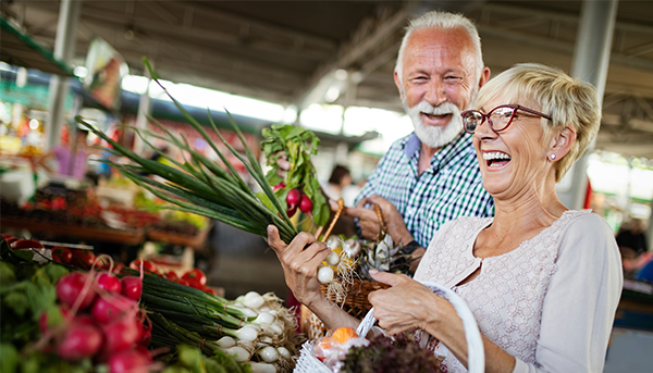 An older couple shop happily at a market.