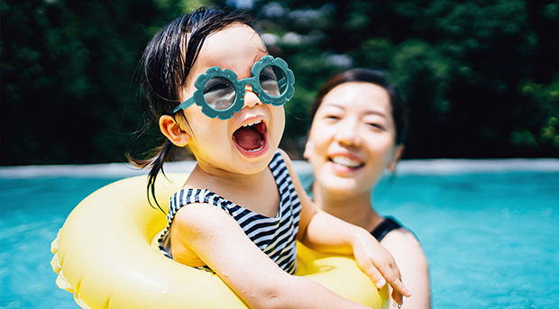 A mother plays with her daughter in a swimming pool.